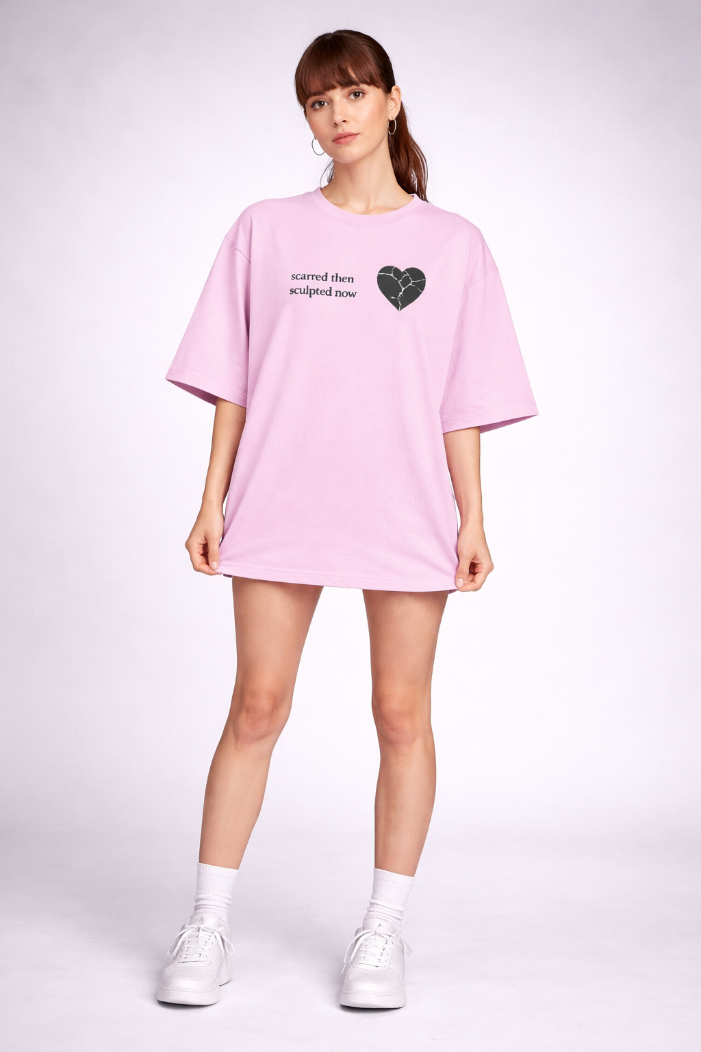Person wearing a pink oversized t-shirt with a heart design on a white background