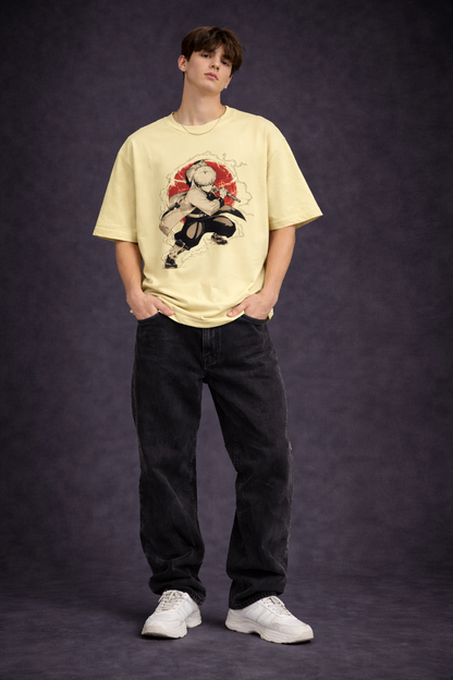 Person wearing a beige t-shirt with a graphic design and black pants on a dark background