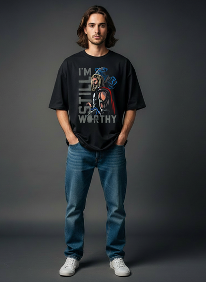 Person wearing a Thor inspired black t-shirt with a graphic design and text, standing against a gray background